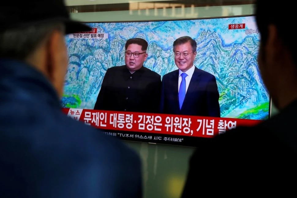 Người dân Seoul (Hàn Quốc) xem bản tin về cuộc gặp thượng đỉnh liên Triều. Tổng thống Hàn Quốc Moon Jae-in (phải) chụp hình chung với lãnh đạo Triều Tiên Kim Jong-un trước bức tranh núi Kim Cương ở Triều Tiên được treo trong Nhà Hòa Bình. Ảnh: REUTERS