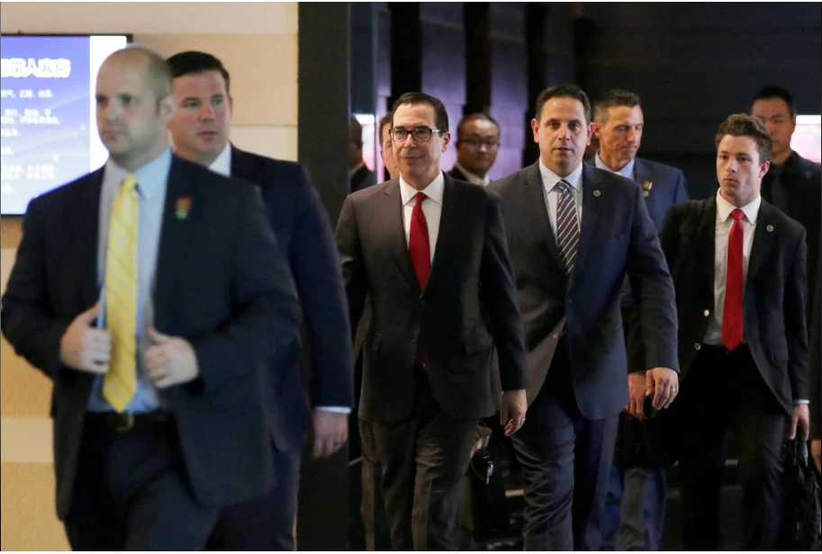 Bộ trưởng Tài chính Mỹ Steven Mnuchin (đeo kính, giữa) và phái đoàn Mỹ từ một khách sạn ở Bắc Kinh đến địa điểm đàm phán. Ảnh: REUTERS