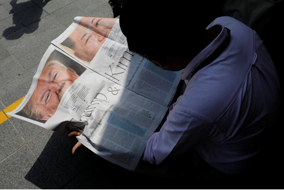 Một nhà báo đọc bản tin về thượng đỉnh Mỹ-Triều trên báo địa phương lúc đang chờ lấy tin gần khách sạn St. Regis – nơi lãnh đạo Triều Tiên Kim Jong-un ở, tại Singapore ngày 11-6. Ảnh: REUTERS