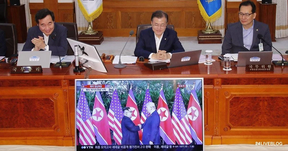 Tổng thống Hàn Quốc Moon Jae-in (giữa) theo dõi cuộc gặp thượng đỉnh lịch sử giữa Tổng thống Mỹ Donald Trump và lãnh đạo Triều Tiên Kim Jong-un qua màn hình, trước khi bắt đầu cuộc họp nội các sáng 12-6. Ảnh: CNA