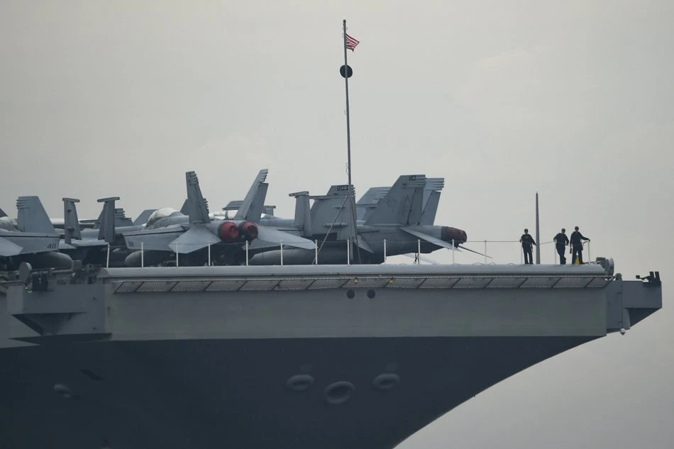 Thủy thủ Mỹ đứng bên cạnh các máy bay chiến đấu F/A-18 Super Hornets đậu trên tàu sân bay USS Ronald Reagan cập Vịnh Manila (Philippines) ngày 26-6. Ảnh: AFP