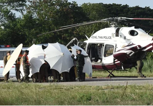 Cảnh sát và quân đội Thái di chuyển một thành viên đội bóng nhí từ trực thăng xuống xe cứu thương tại một căn cứ quân sự ở Chiang Rai ngày 9-7. Ảnh: AFP