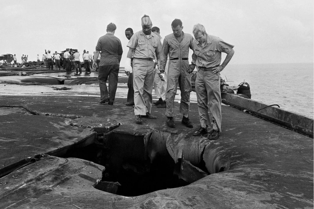 Thiếu tá hải quân John McCain (phải) cùng các đồng nghiệp Robert Browning (trái), Kenneth McMillen (giữa) xem xét hư hại trên con tàu sân bay USS Forrestal – nơi đã xảy ra tại nạn nghiêm trọng tháng 7-1967 giết chết 134 và làm bị thương 161 thủy thủ trên tàu. Phi công McCain đã may mắn thoát được. Ảnh: GETTY IMAGES