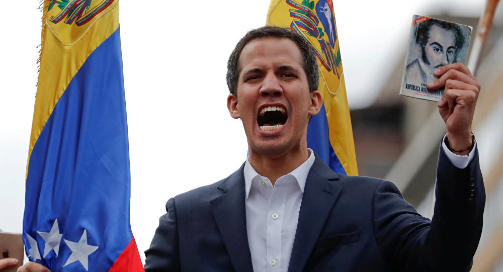 Chủ tịch Quốc hội Venezuela, lãnh đạo đối lập Juan Guaido giơ cao bản Hiến pháp Venezuela khi tham gia tuần hành chống chính phủ ở thủ đô Caracas (Venezuela) ngày 23-1, ngày ông tuyên bố mình là tổng thống lâm thời. Ảnh: REUTERS