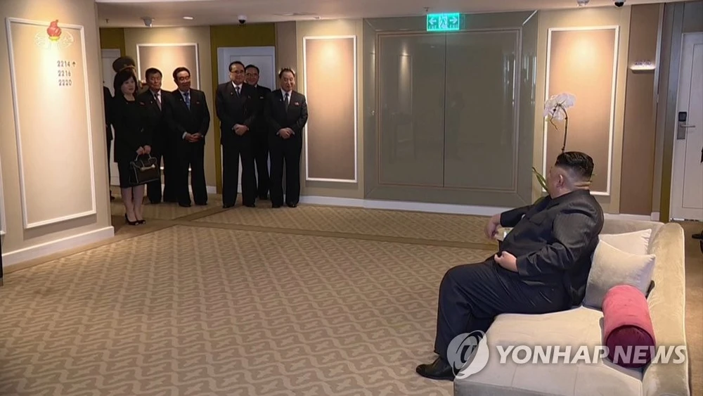 Các quan chức Triều Tiên đứng nghe chỉ đạo từ lãnh đạo Triều Tiên Kim Jong-un (ngồi, phải) tại khách sạn Melia ở Hà Nội. Ảnh: YONHAP chụp lại từ màn hình đài truyền hình trung ương Triều Tiên KCTV