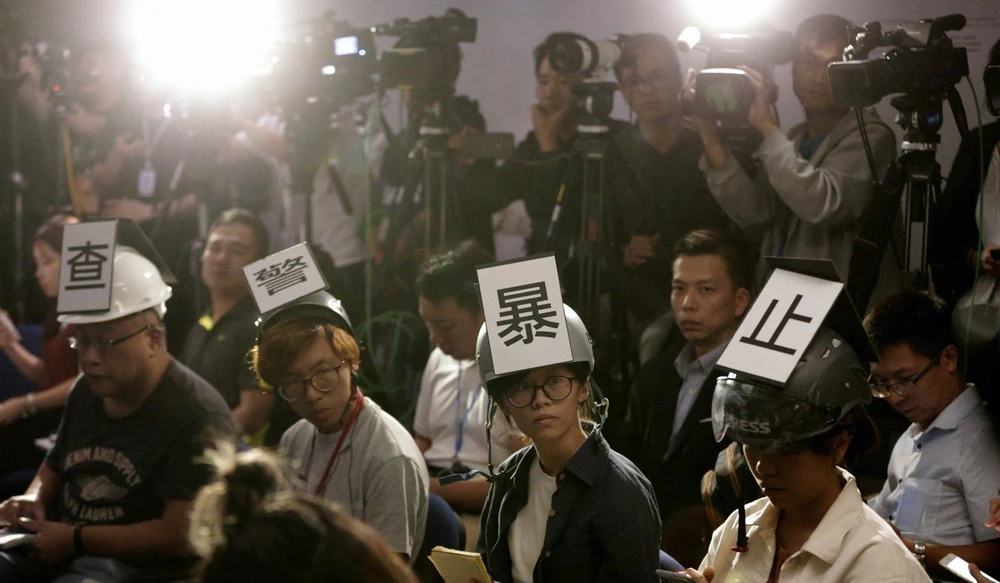 Các nhà báo đội nón bảo hiểm có dòng chữ mang nội dung “Điều tra sự bạo lực của cảnh sát”, phản đối bạo lực của cảnh sát với cánh nhà báo, trong khi tham gia một cuộc họp báo của cảnh sát ở Hong Kong ngày 4-11. Ảnh: AP