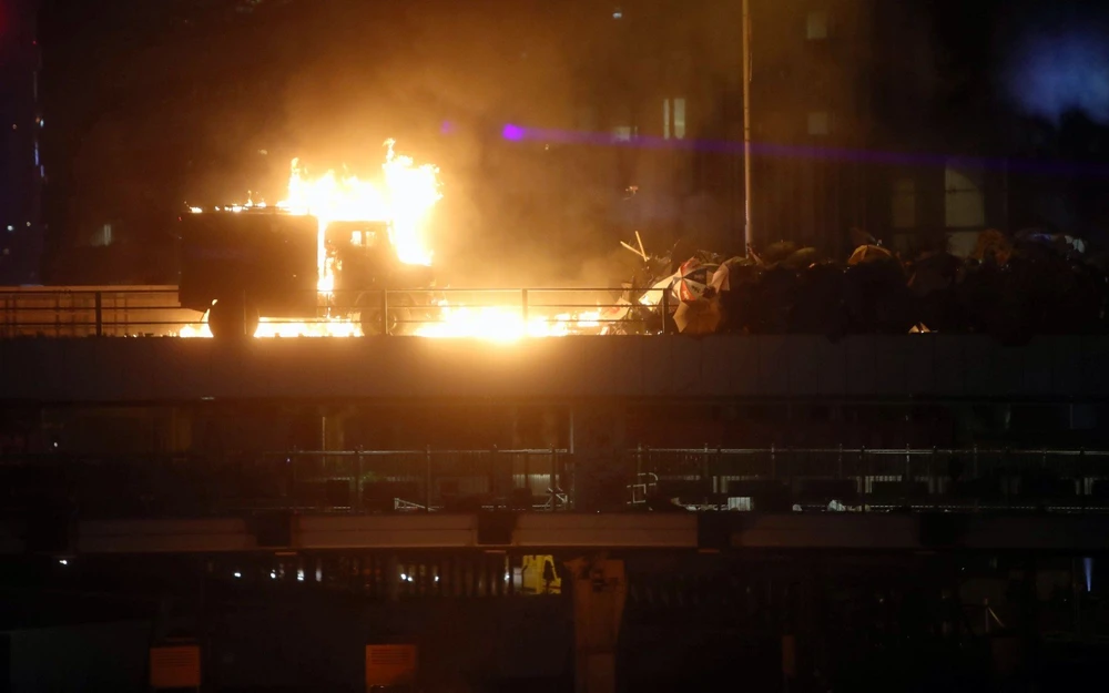 Một xe cảnh sát bị phóng hỏa trong khi cảnh sát và người biểu tình xung đột trên một cây cầu tại khu vực trường đại học Bách Khoa, ngày 17-11. Ảnh: SCMP