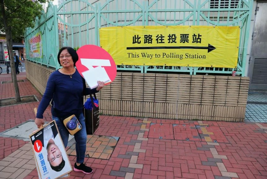 Một phụ nữ vận động cho một ứng viên bên ngoài một địa điểm bỏ phiếu trong cuộc bầu cử địa phương ở Hong Kong sáng 24-11. Ảnh: REUTERS