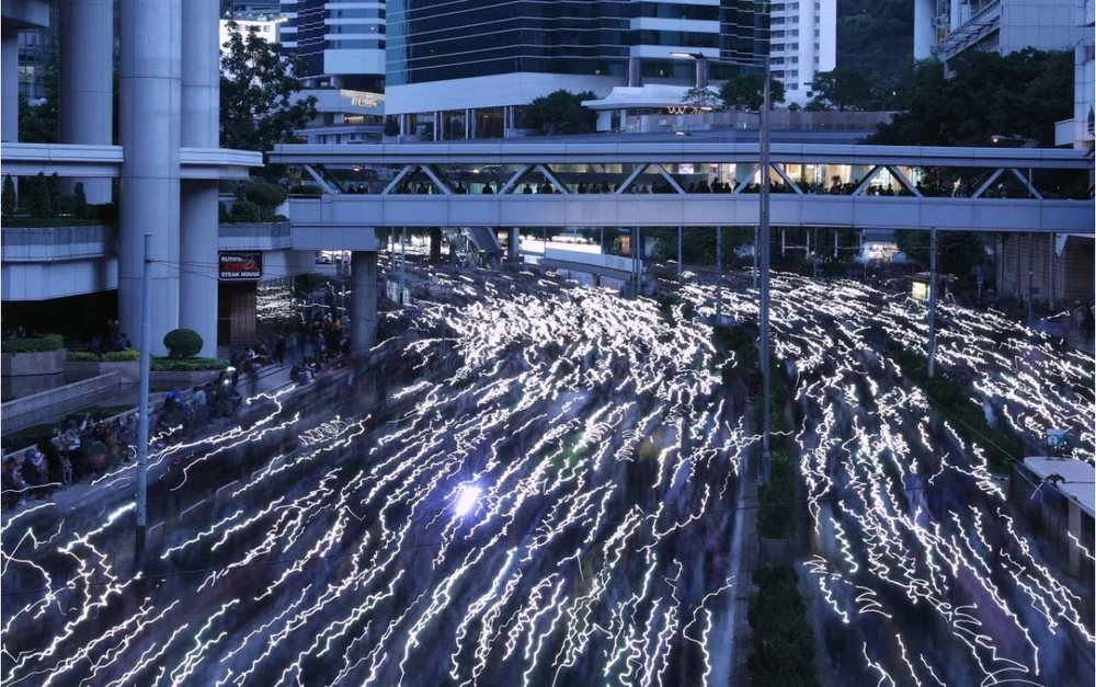 Người biểu tình dùng đèn điện thoại tạo dòng ánh sáng trên đường phố, tối 8-12. Ảnh: SCMP