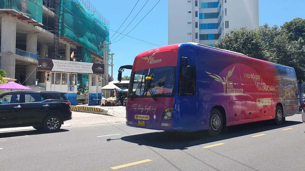 Xe khách dán kín quảng cáo dự án bất động sản chạy trên đường Lê Thánh Tôn, TP Nha Trang. Ảnh: HH.