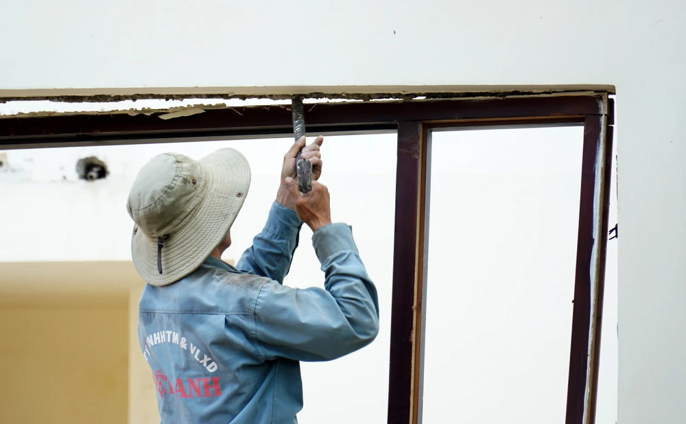 Các khung cửa và cửa bằng gỗ được các công nhân cẩn thận cạy ra để thu hồi.