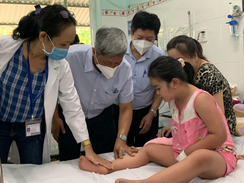 Thứ trưởng Bộ Y tế Nguyễn Trường Sơn đang thăm hỏi một bệnh nhi điều trị sốt xuất huyết ở Bệnh viện Quận 8. Ảnh: HOÀNG LAN