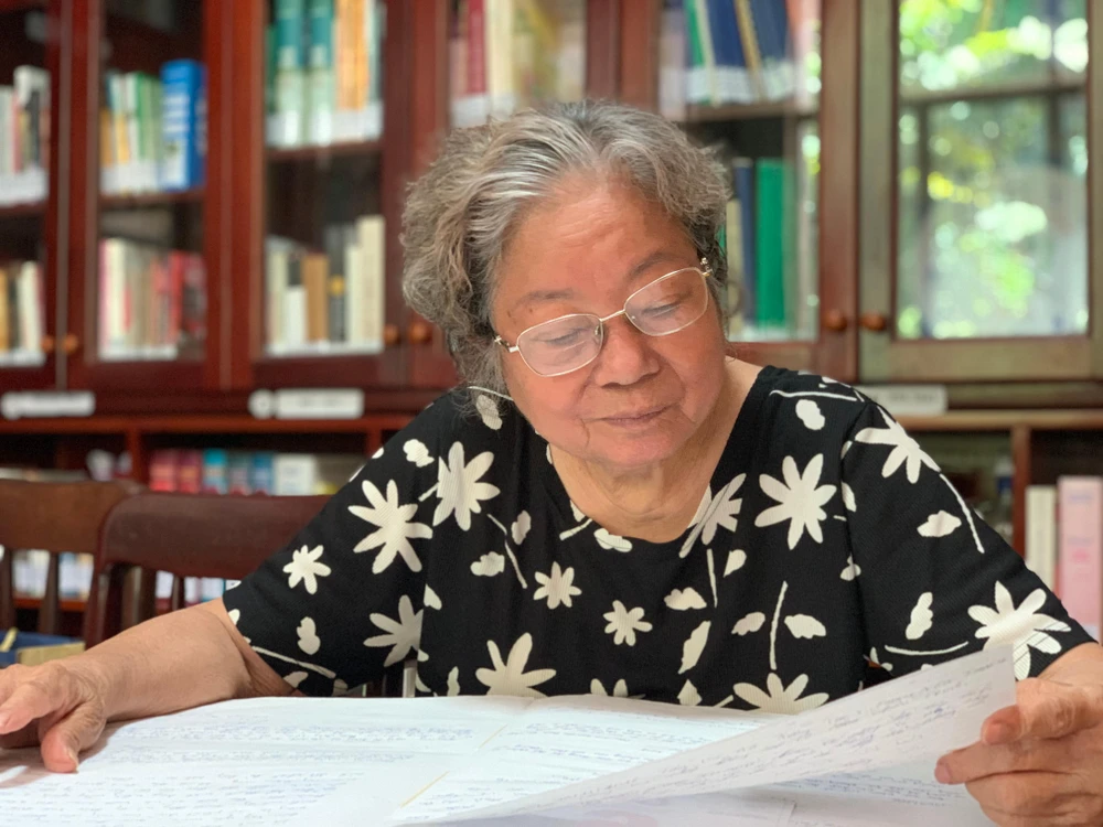 Bà Lê Thị Sáu giữ gìn nâng niu những trang lưu bút của khách tham quan khi viếng mộ cụ Phan Châu Trinh. Ảnh: GIA NGHI