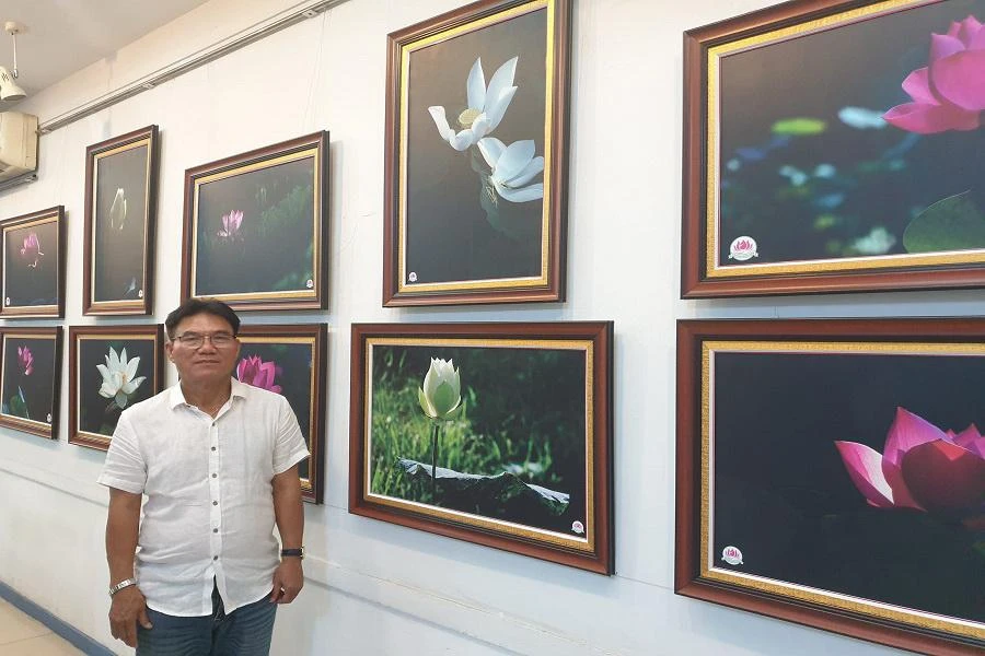 Nhiếp ảnh gia Thành Xuân Anh bên cạnh những tác phẩm về hoa sen của mình. Ảnh: VĂN HÀ