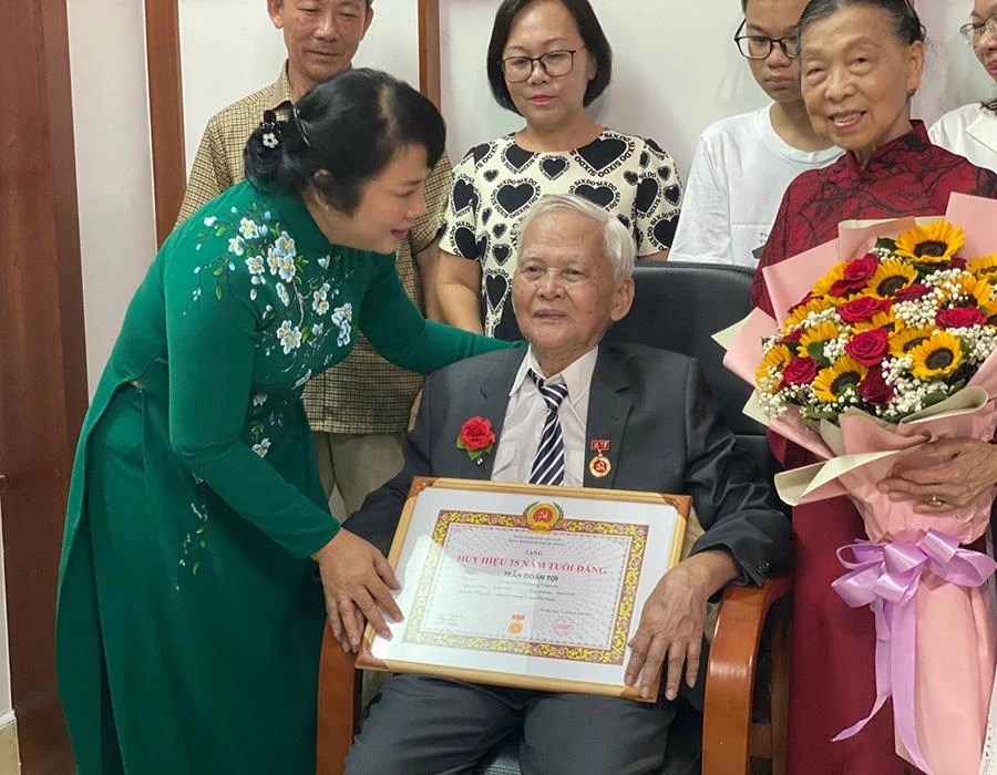 Bà Trần Kim Yến, Chủ tịch Ủy ban MTTQ Việt Nam TP.HCM, trao huy hiệu Đảng và bằng khen cho ông Trần Doãn Tợi. Ảnh: NGUYỄN YÊN