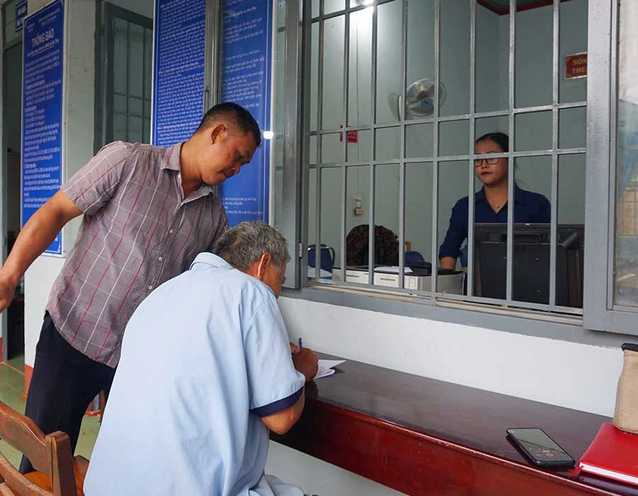 Ông Nguyễn Khắc Pha làm giấy tờ khám bệnh cho cháu tại UBND xa Ea Tiêu ngày 15-6. Ảnh: VŨ LONG