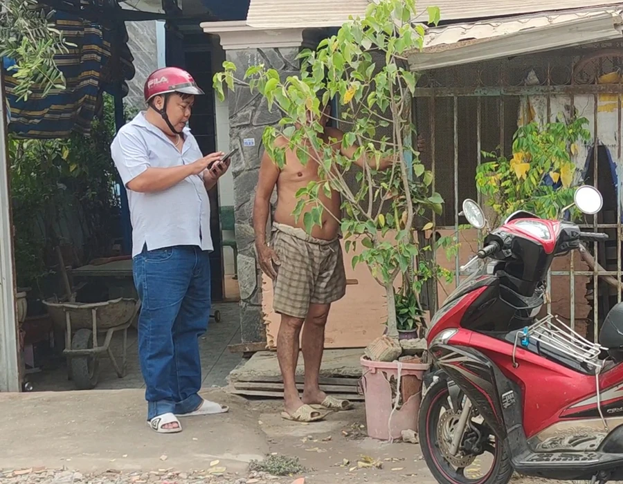 Anh Tâm đang hỏi người dân địa chỉ công ty theo cấp giấy chứng nhận đăng ký kinh doanh. Ảnh: NGUYỄN HIỀN