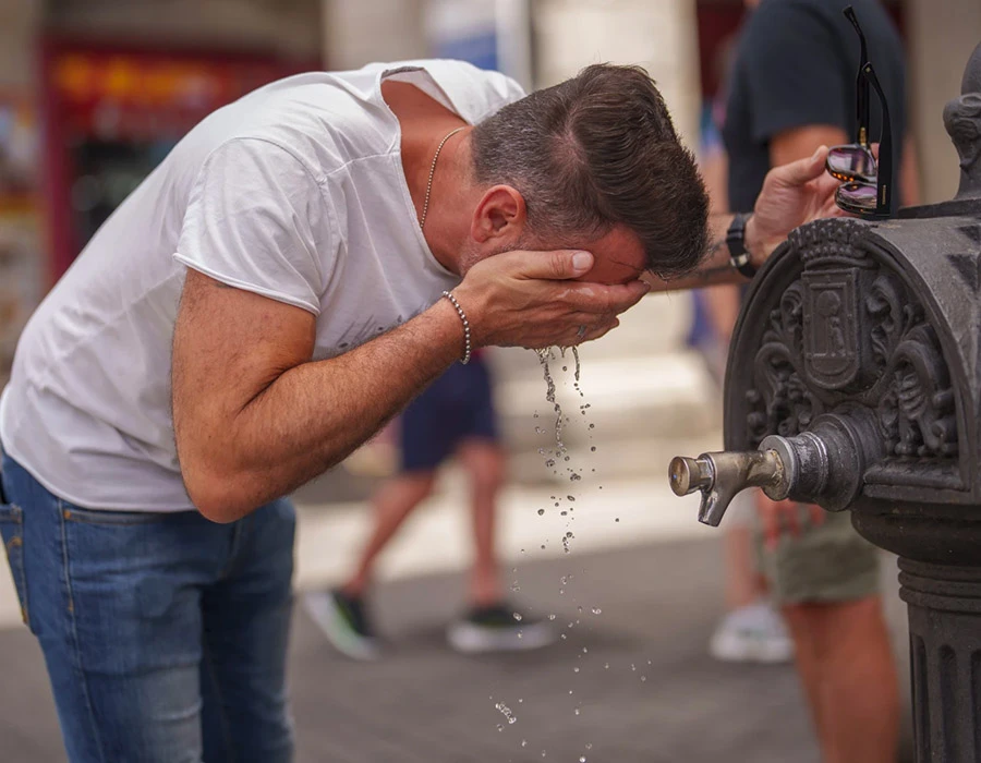 Một người dân rửa mặt tại vòi nước công cộng ở TP Madrid (Tây Ban Nha) để làm mát. Ảnh: AP