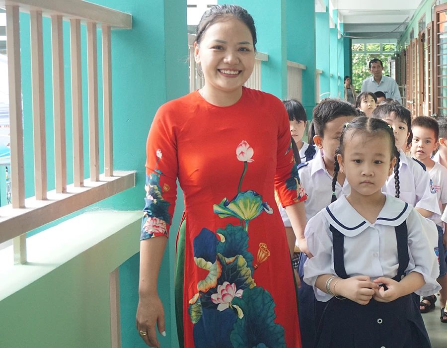 Cô giáo Trường Tiểu học Lam Sơn, quận Gò Vấp dẫn học sinh lớp 1 tham quan các phòng học sáng 14-8. Ảnh: NGUYỄN QUYÊN