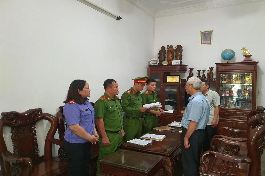 Công an đang đọc quyết định khởi tố bị can. Ảnh AL