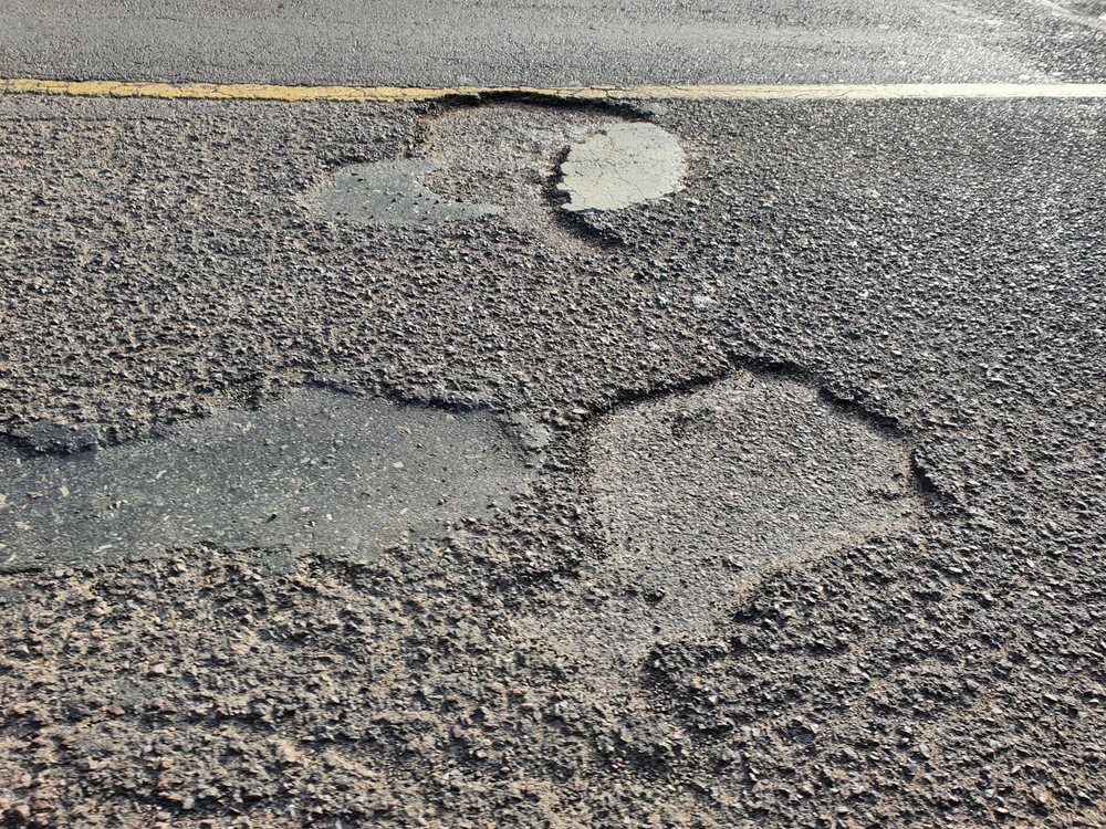 Đường xuất hiện nham nhở nhiều địa điểm lồi lõm, bề mặt đường liên tiếp bong tróc nhiều mảng lớn. Ảnh QN