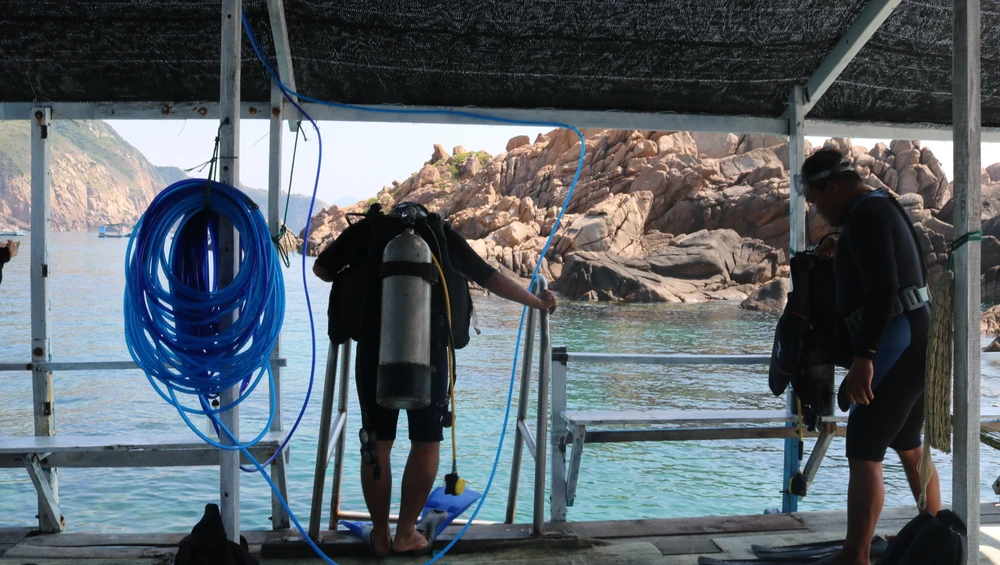 Sau khi hoàn tất việc chuẩn bị kỹ lưỡng, các anh lần lượt lặn xuống biển để bắt đầu công việc. Ảnh QN