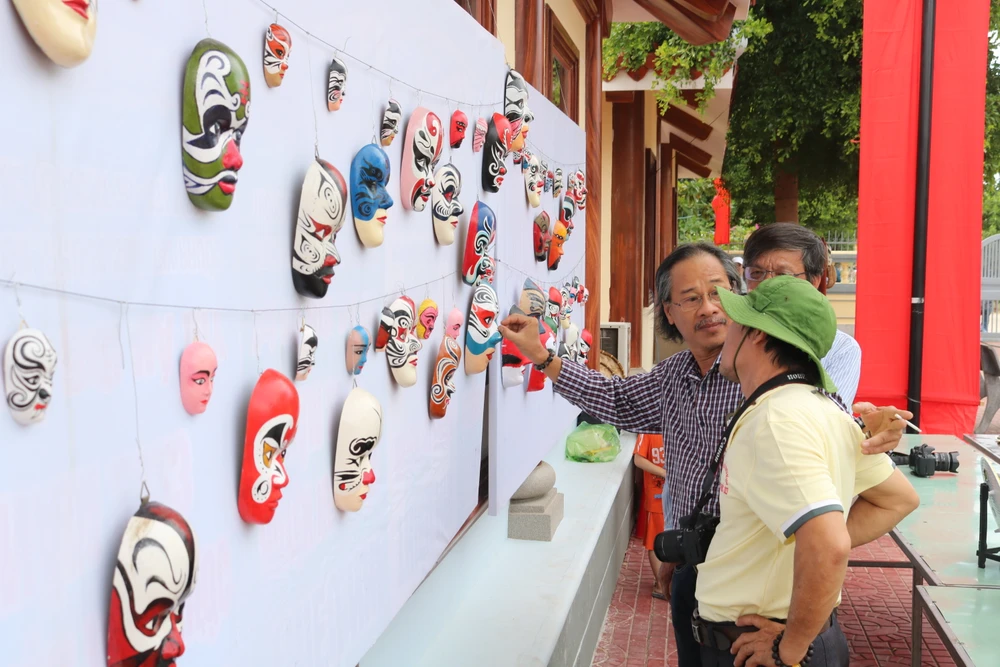 Khách thích thú với những chiếc mặt nạ được trưng bày. Ảnh QN