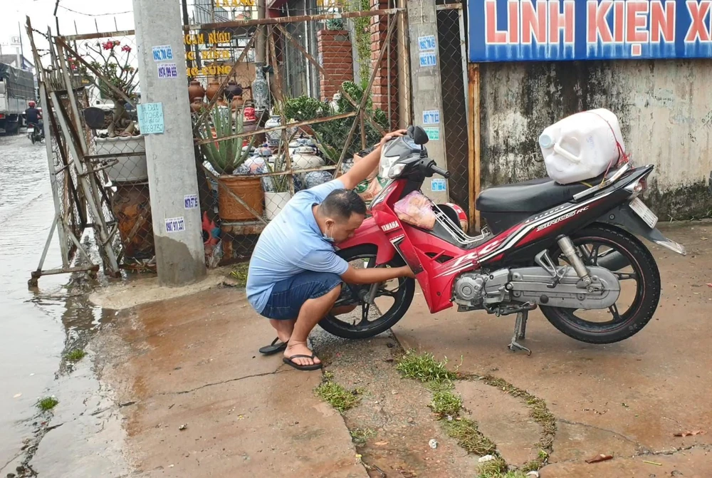 Xe máy bị chết máy do ngập nước, người dân loay hoay tìm cách sửa chữa. Ảnh: LA