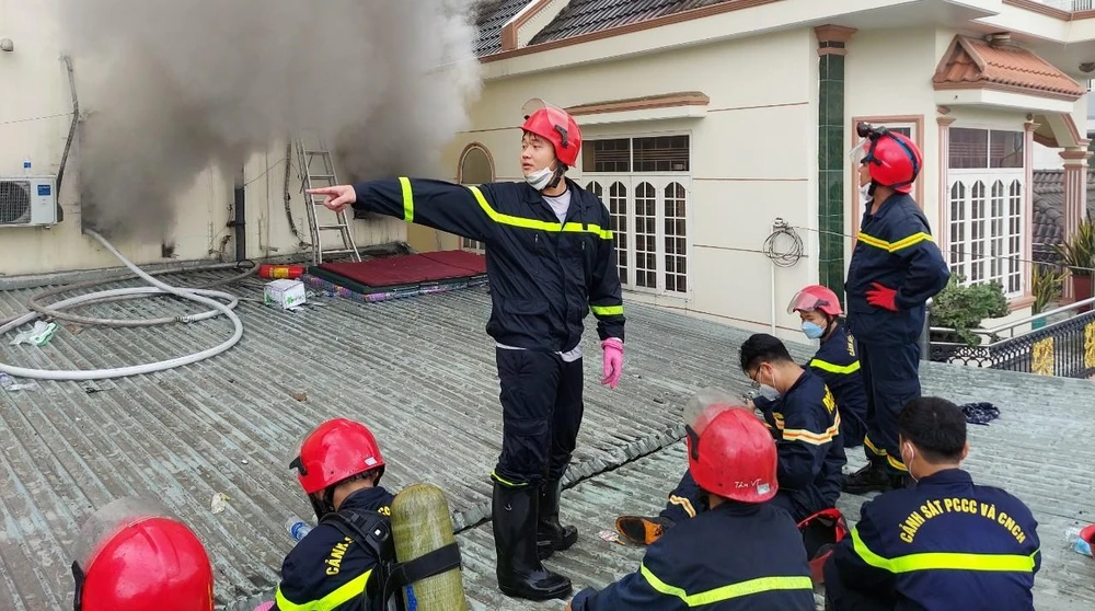 Một nhóm cứu hộ đang tiếp cận đám cháy từ mái nhà bên cạnh để tìm kiếm các nạn nhân.