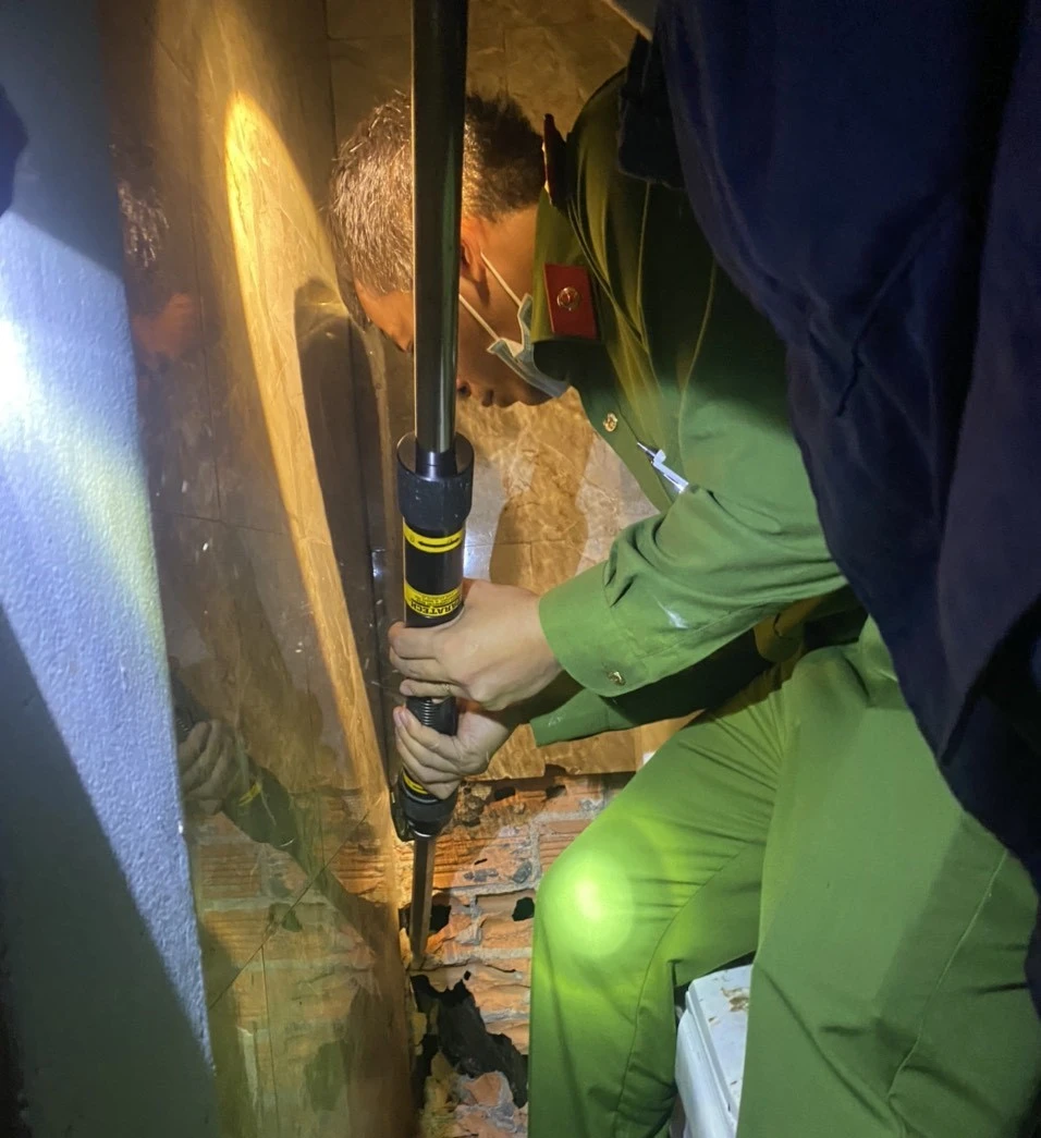 Lực lượng công an phải phá tường để gửi cứu nam thanh niên. Ảnh: CACC