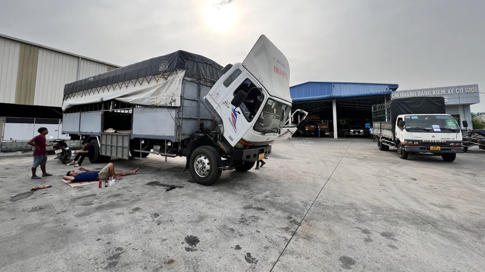 Tài xế trải chiếu nằm trong trong sân Trung tâm đăng kiểm xe cơ giới 61-03S. Ảnh: LÊ ÁNH