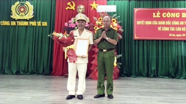 Đại tá Trần Văn Chính (phải) phó Giám đốc Công an TP Dĩ An trao quyết định bổ nhiệm của Giám đốc Công an tỉnh Bình Dương cho thượng tá Đàm Bảo Quân. Ảnh: LA