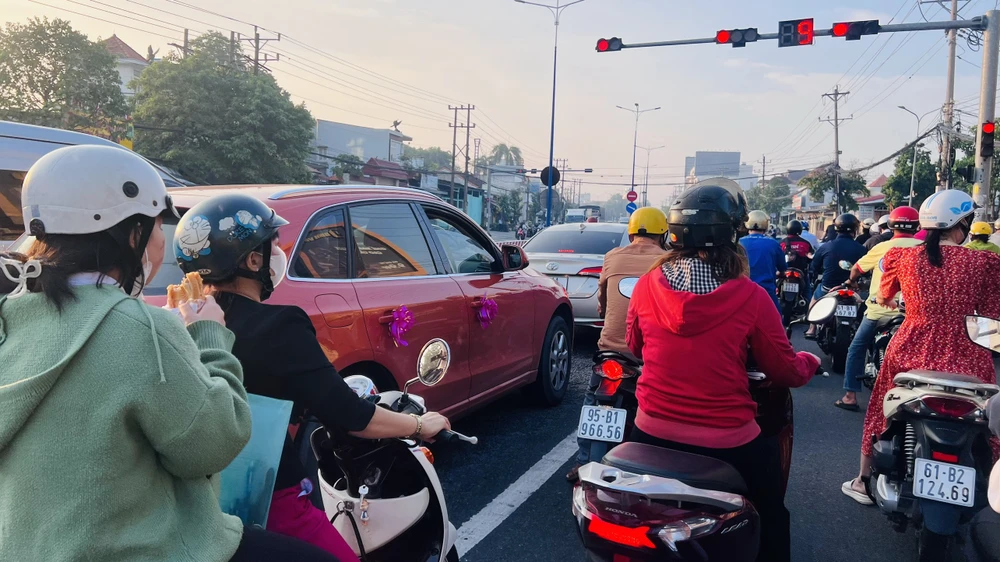 Sĩ tử tranh thủ ăn bánh mì lót dạ trên đường đến điểm thi. Ảnh: LÊ ÁNH