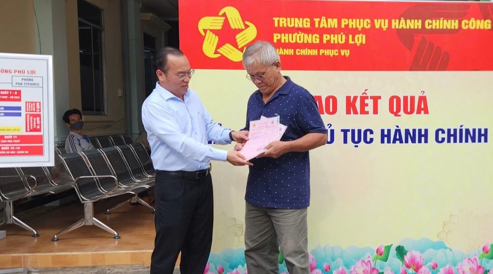 Ông Phan Công Khanh (trái), Chủ tịch UBND phường Phú Lợi trao sổ hồng được cấp mới cho người dân.