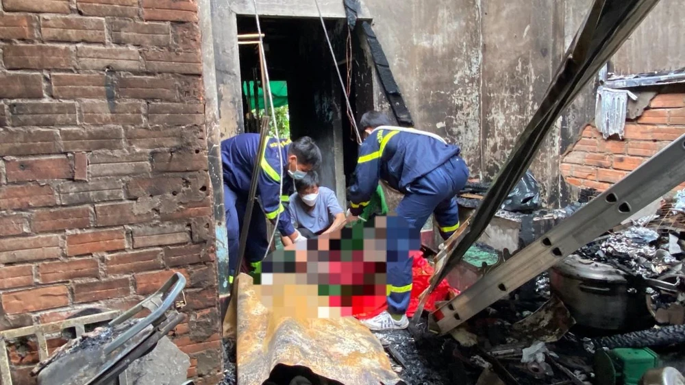 Lực lượng chức năng đưa thi thể nạn nhân ra khỏi nhà. Ảnh: HD