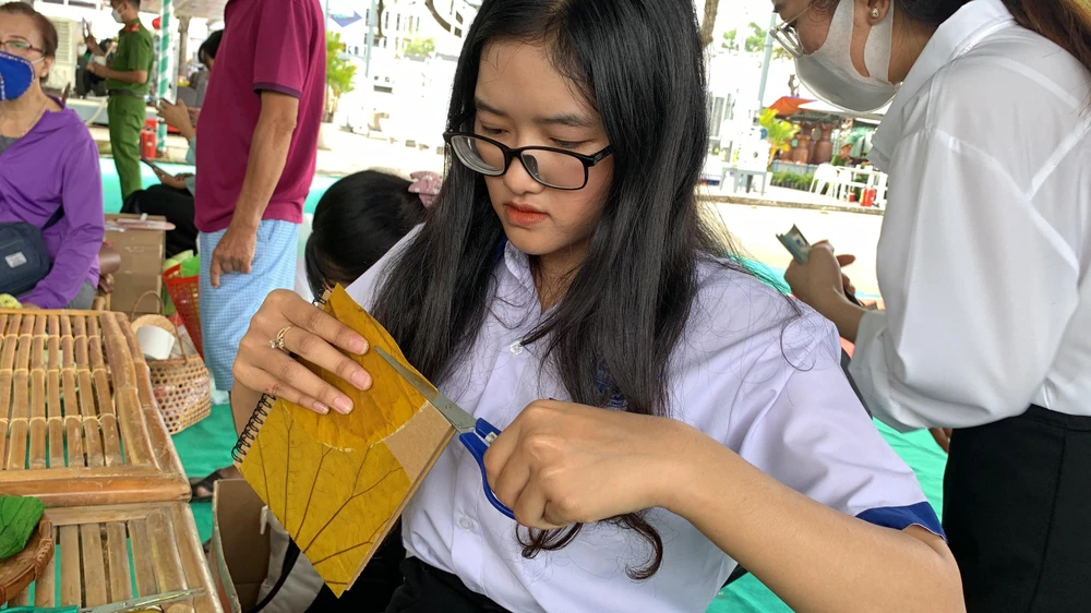 Một em học sinh cũng chăm chú thiết kế bìa sổ của mình bằng lá sen