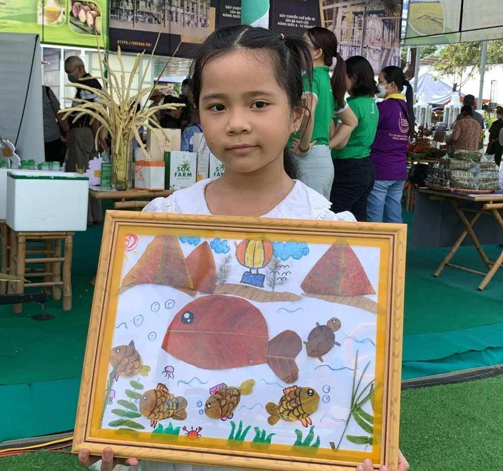 Khoe bức tranh cá voi mình cùng các bạn sáng tác, em Minh Tuyền cho biết tranh được tạo bằng lá vì các em biết được lá cây thân thiện với môi trường