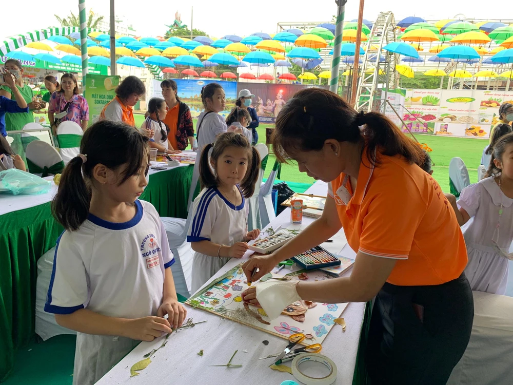 Giáo viên hướng dẫn các em học sinh vẽ tranh từ lá