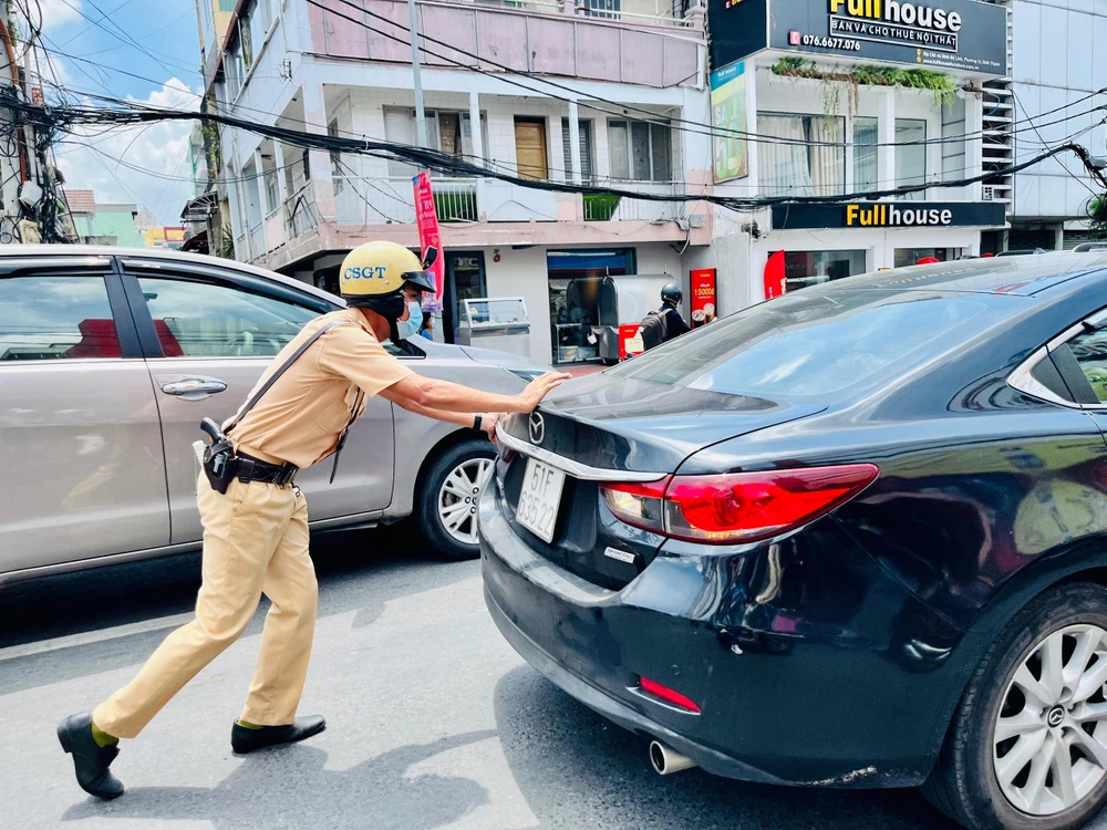 Tổ công tác giúp người đàn ông đẩy chiếc xe chết máy. Ảnh: LÊ THOA