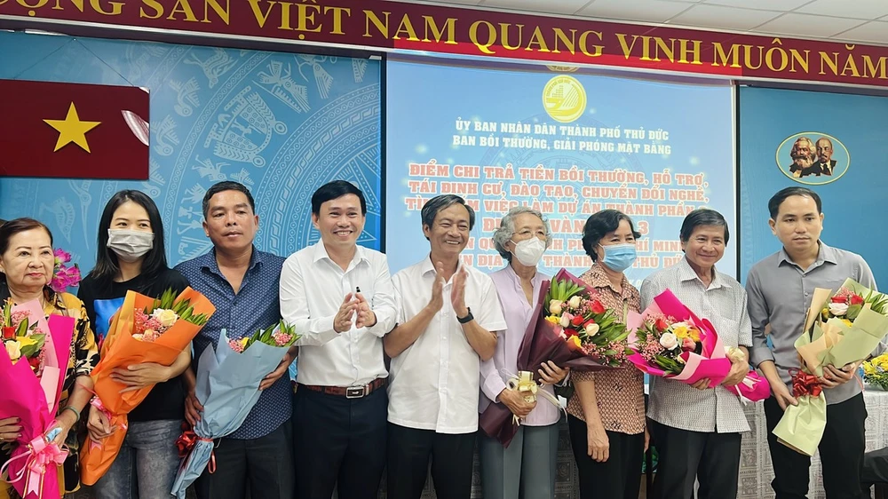 Ông Võ Trung Trực, Phó Giám đốc Sở TN&amp;MT và ông Nguyễn Hữu Anh Tứ, Phó Chủ tịch UBND TP Thủ Đức trao hoa cho các tổ chức, cá nhân nhận tiền bồi thường dự án vành đai 3 sáng ngày 8-5. Ảnh: ĐÀO TRANG