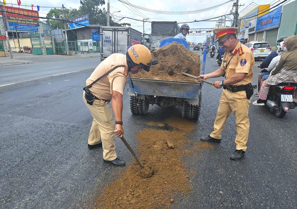 Người dân trượt té vì vệt nhớt, CSGT Tân Túc dang nắng rải cát xuống đường-csgt-rai-cat
