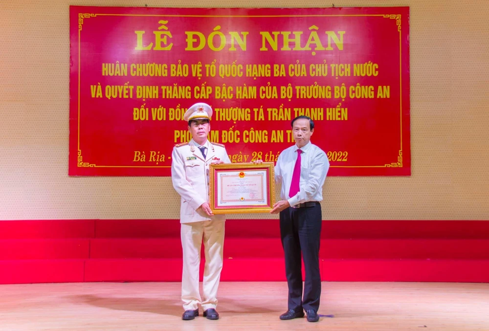 Ông Nguyễn Văn Thọ thừa ủy quyền của Chủ tịch nước trao quyết định cho thượng tá Trần Thanh Hiển. Ảnh: LƯU TRUNG