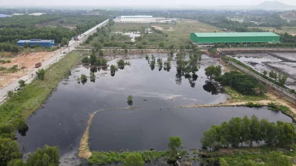 Một đoạn tường rào hồ chứa chất thải bị vỡ khiến nước tràn ra khu đất lân cận và suối Giao Kèo, hướng về đập Châu Pha-Ảnh:HS