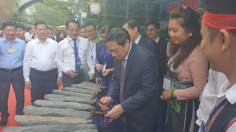 Thủ tướng gõ đàn đá tại gian trưng bày của tỉnh Bình Phước. Ảnh: TK