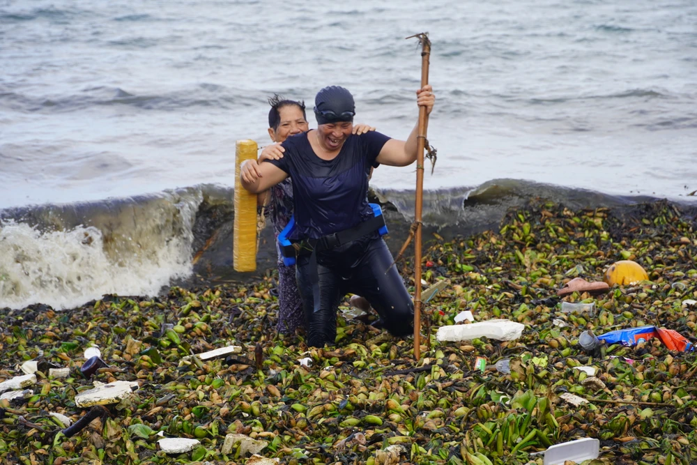 Vượt "tấm thảm" rác để vào bờ sau khi tắm xong. Ảnh: TĐ