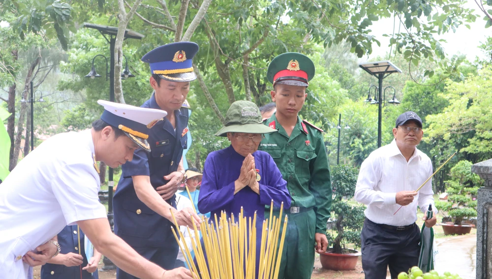 Cụ Phan Thị Lý xúc động khi thắp nén nhang cho các liệt sĩ. Ảnh: TK