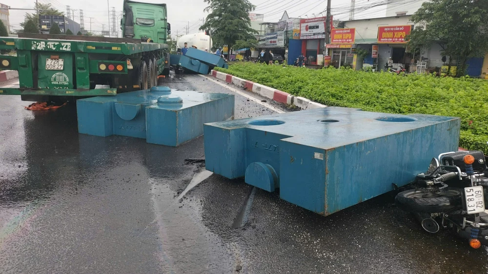 Một người đi xe mô tô bị thương khi cục sắt to trên xe container 'bay' xuống đường