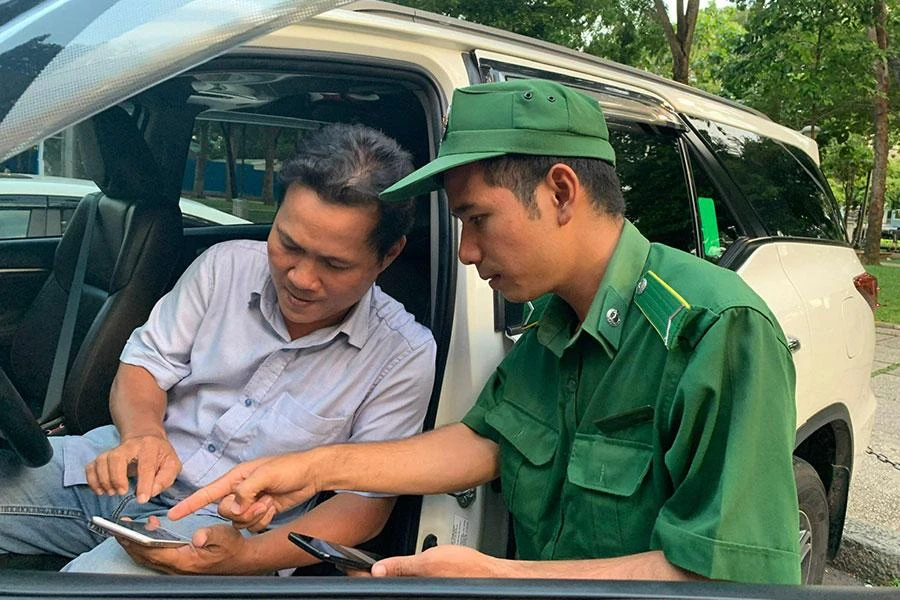 Nhân viên Công ty TNXP hướng dẫn chủ xe cài app để sử dụng dịch vụ thu phí đỗ ô tô dưới lòng được. Ảnh: ĐL