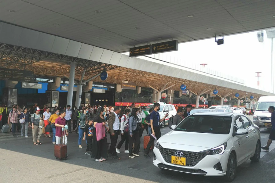 Dòng khách tấp nập băng qua làn di chuyển của ô tô tại sân bay Tân Sơn Nhất. Ảnh: P.ĐIỀN