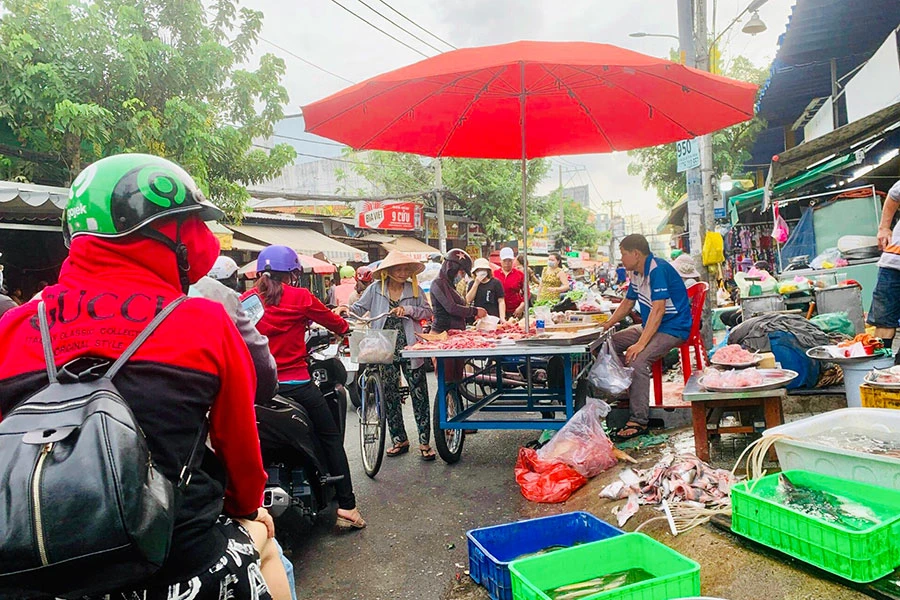 Khoảng 6 giờ sáng, đường Hương lộ 2 rất đông người mua bán dưới lòng đường. Ảnh: TRẦN MINH
